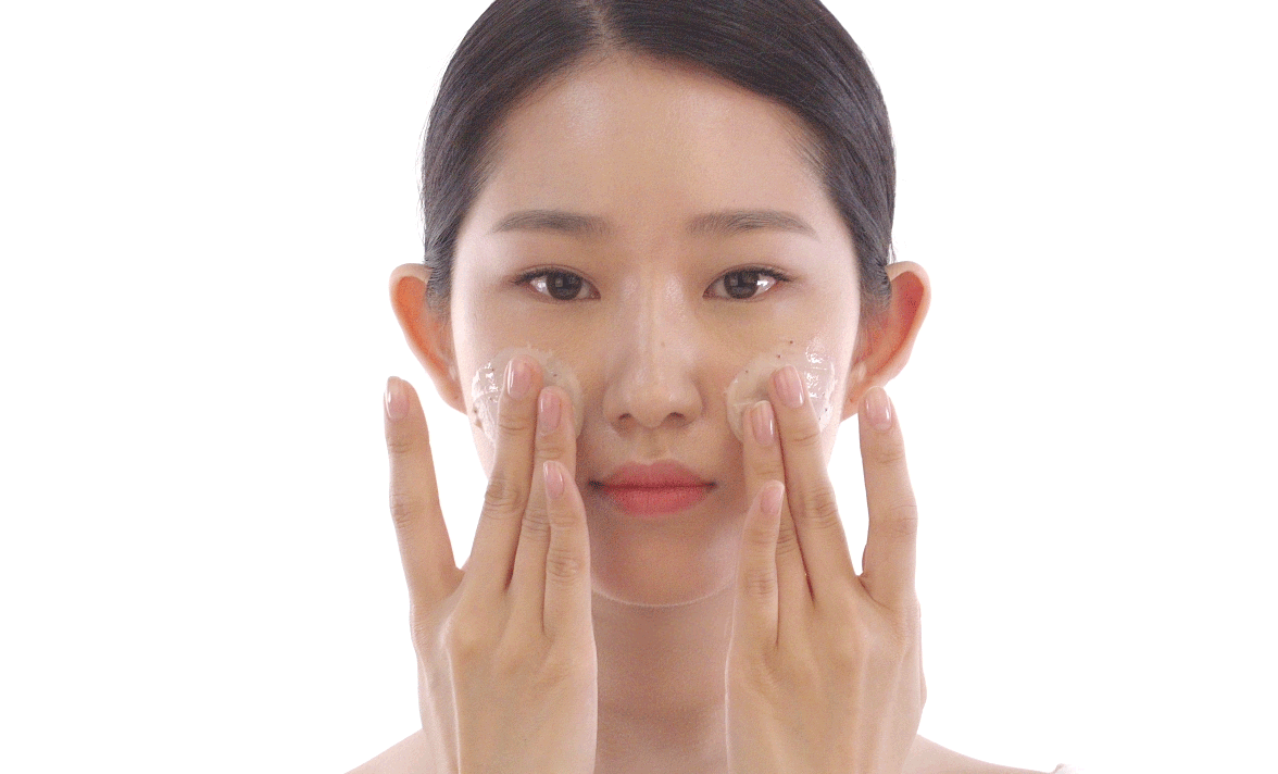 A woman applying facial scrub to her face
