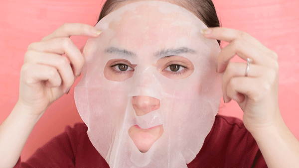 A woman applying sheet mask on her face